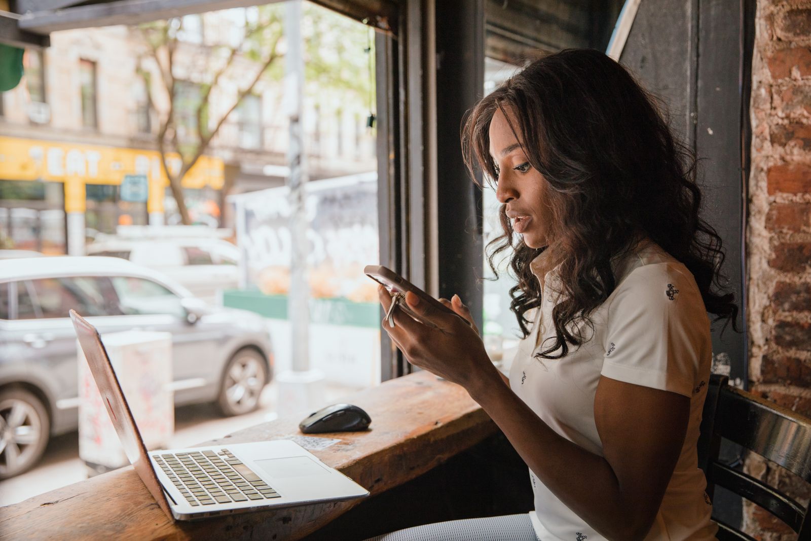 Woman using laptop and smart phone at cafe