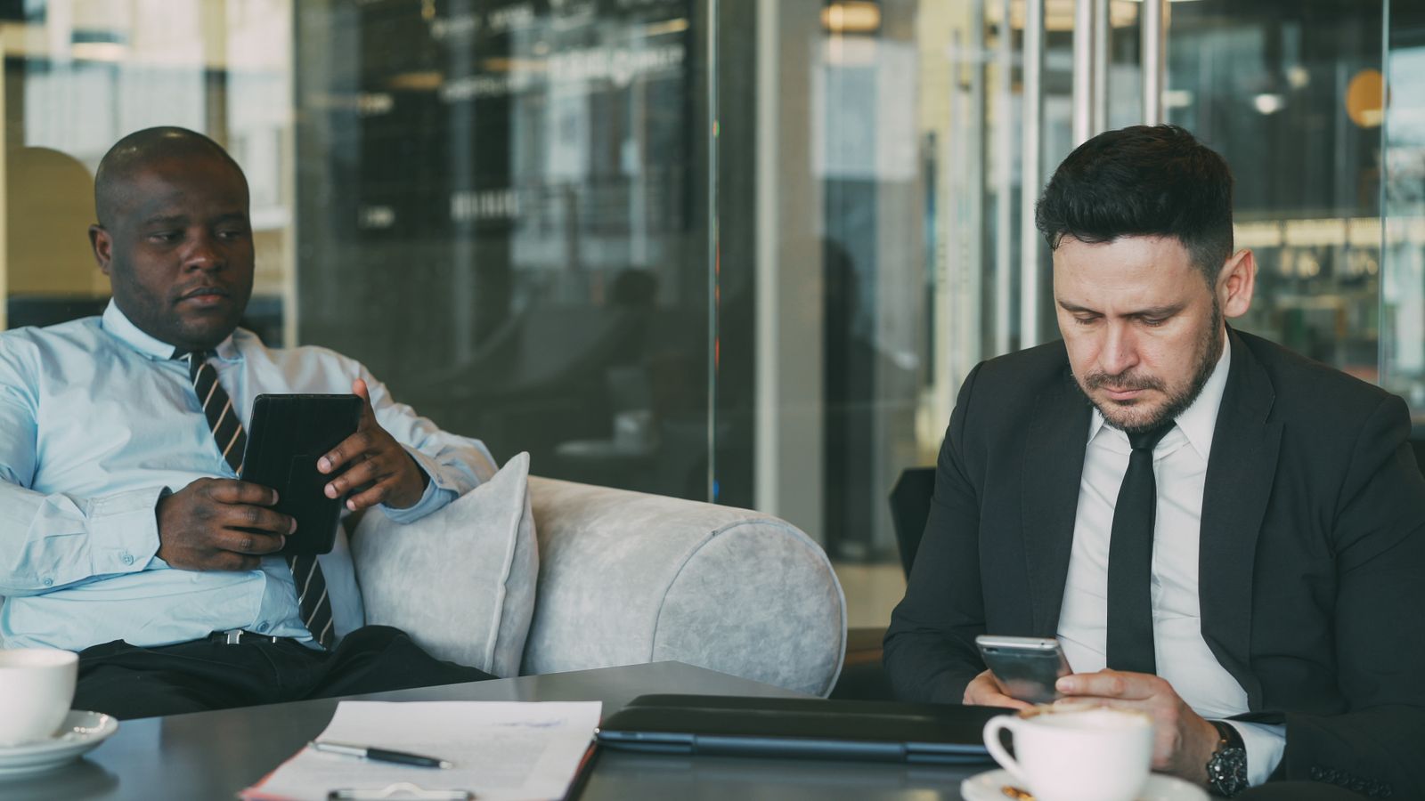 Businessmen using mobile devices in office lounge