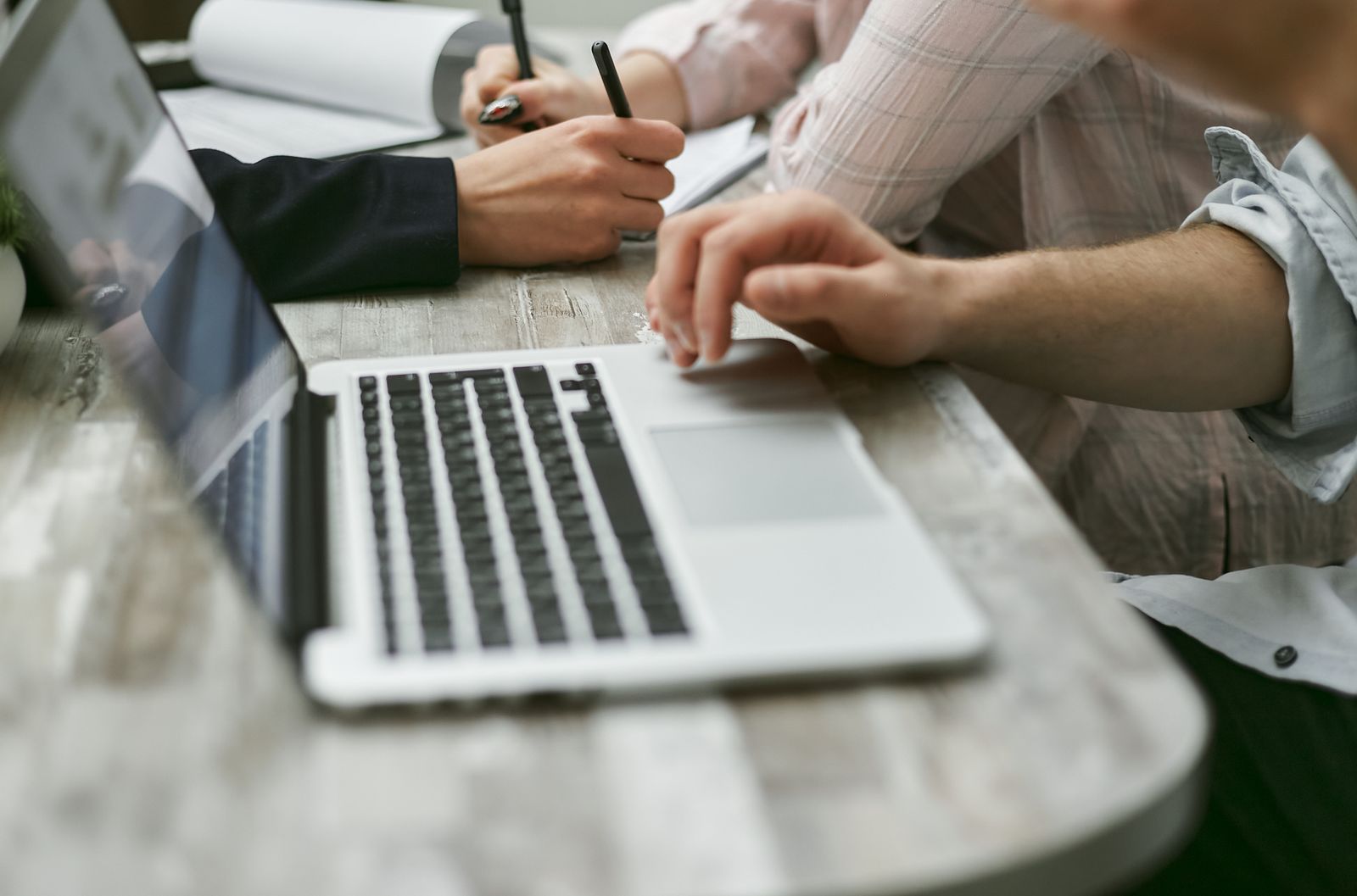 Unrecognizable coworkers using netbook and writing information on papers